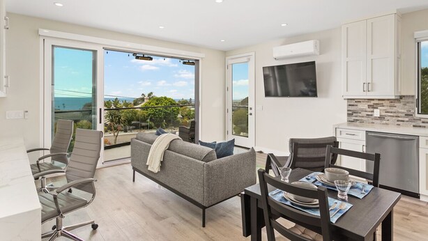 A modern apartment with a dining area, sofa, and kitchen.