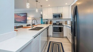 Una cocina moderna con armarios blancos, electrodomésticos de acero inoxidable e iluminación colgante.