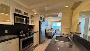 A modern kitchen with stainless steel appliances, a large island, and a view to the living area. - Delightful Gulf views from the 11th floor!-WS1102 (Naples)
