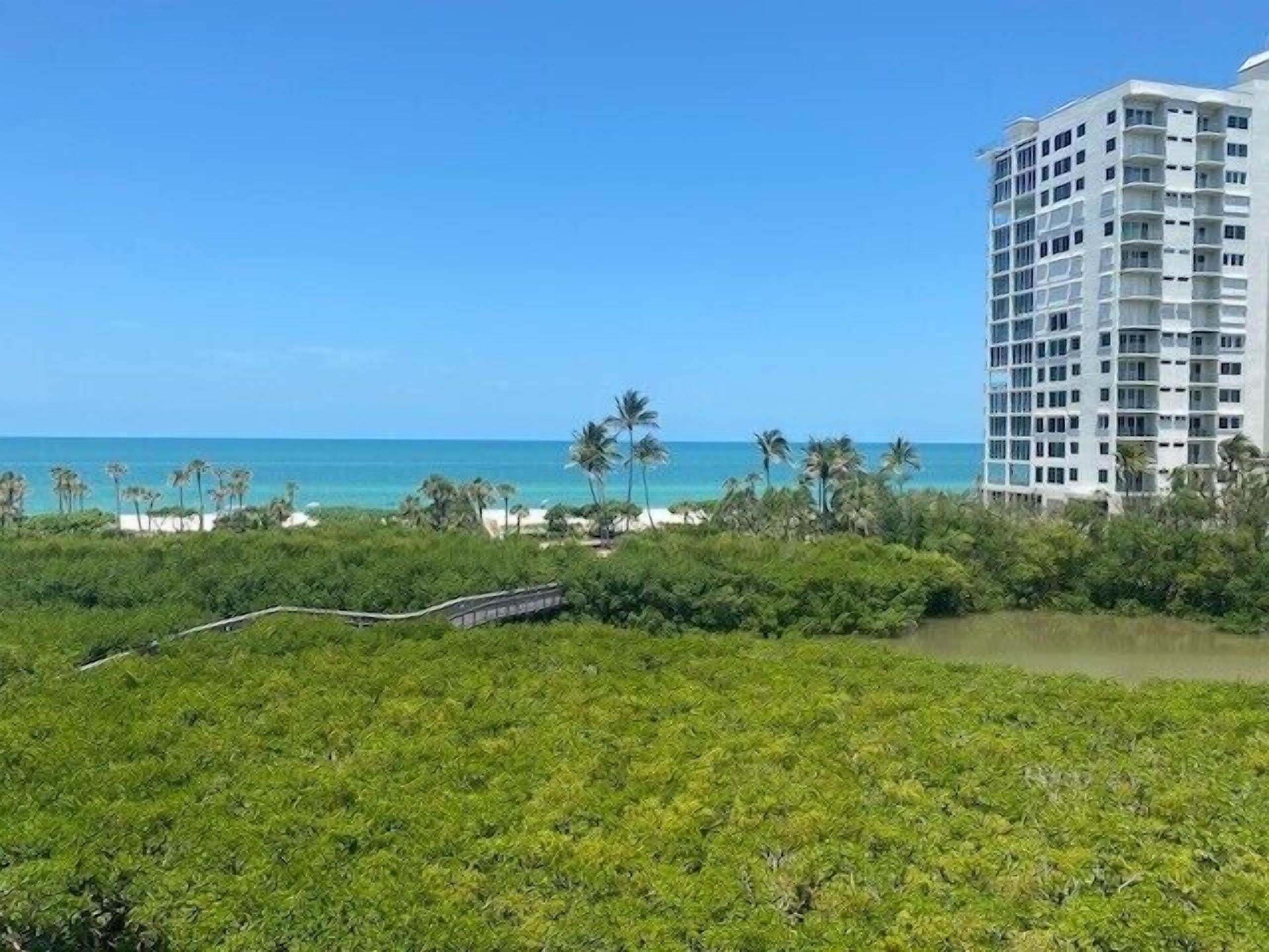 Een hoog hotel met uitzicht op de oceaan en palmbomen.