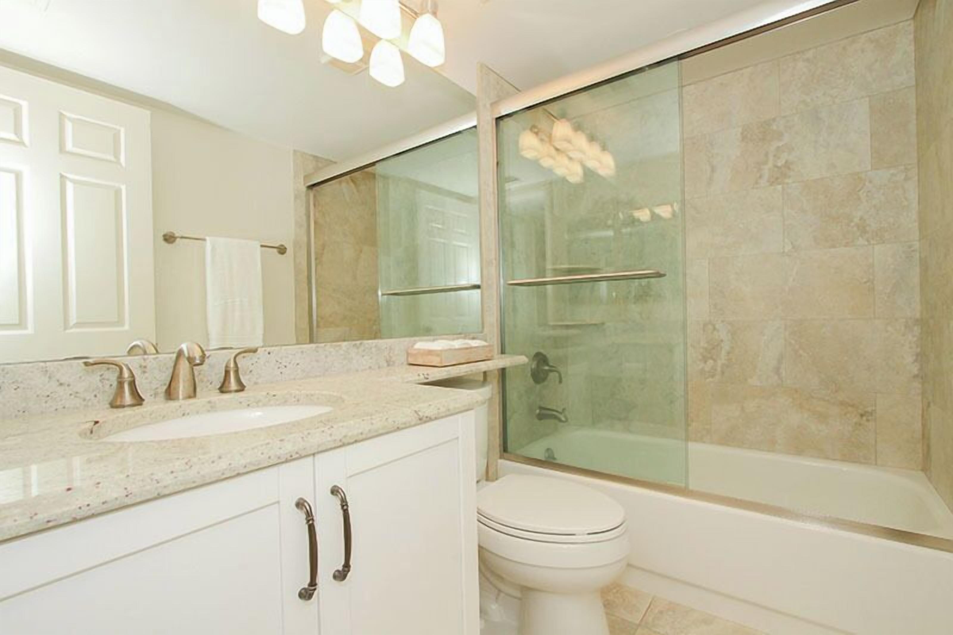 Un baño con ducha de vidrio, un lavabo blanco y un inodoro.