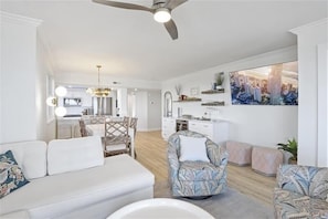 A spacious living area with a white sofa, patterned armchairs, and a dining area with a chandelier. - Magnificent views of the Gulf & Clam pass!- WS0804 (Naples)