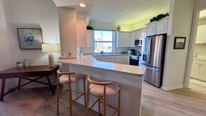 Una cocina moderna con una isla central, electrodomésticos de acero inoxidable y vistas a la ciudad desde la ventana.