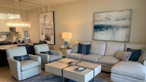 Ein modernes Wohnzimmer mit einer Couch, Sesseln, einem Couchtisch und Bildern an den Wänden.