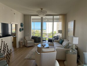 Un salon spacieux avec balcon, une télévision et un coin repas.