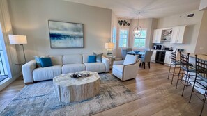 A modern living room with a sofa, coffee table, and chairs, a dining area with a table and chairs, and a kitchen with cabinets and appliances. - Beautiful 3-bedroom condo walking distance to the beach - Reg 4-PH4 (Naples)