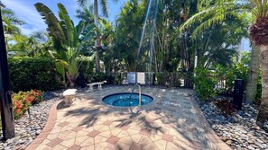 Ein Swimmingpool, umgeben von tropischen Pflanzen und einer Steinterrasse.