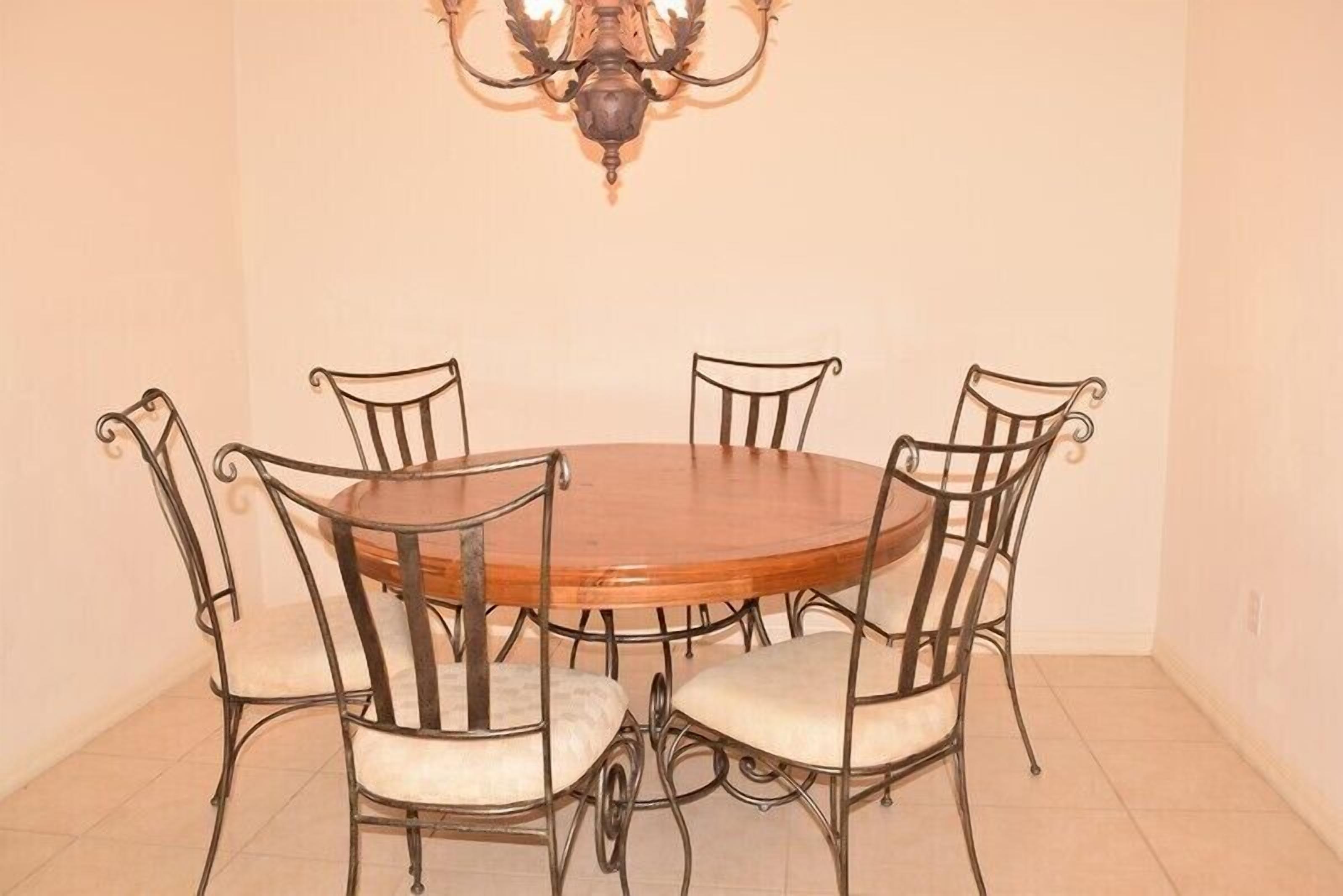 A dining area with a round wooden table surrounded by four upholstered chairs with metal frames.