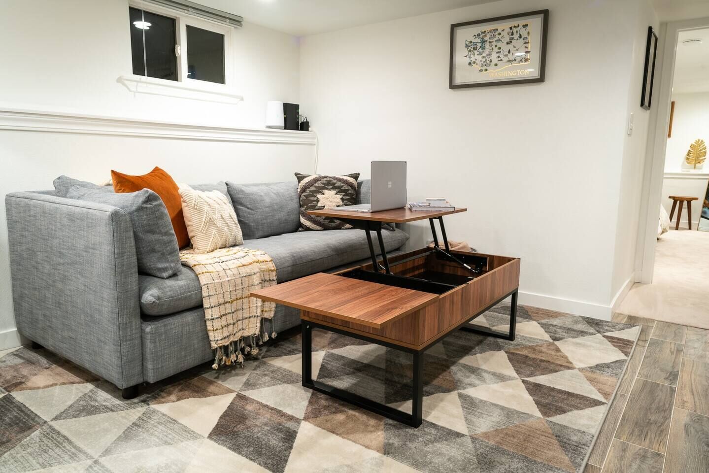 A modern living room with a gray sofa, a wooden coffee table, and a patterned rug.