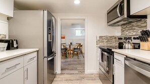 A modern kitchen with stainless steel appliances, a tiled backsplash, and a dining area visible through an open doorway. - Enjoy everything Seattle has to offer in centrally located Central District (Seattle)