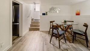 A modern kitchen with a built-in refrigerator, a dining area with a glass table and wooden chairs, and a staircase leading to an upper level. - Enjoy everything Seattle has to offer in centrally located Central District (Seattle)