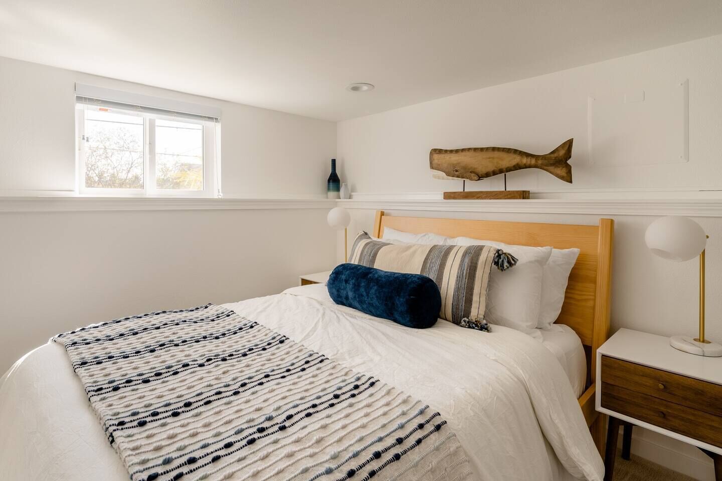 Une chambre à coucher comprenant un lit, une table de chevet, une lampe, une fenêtre et un décor mural représentant des poissons.