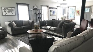 A spacious living room with two grey sofas, a coffee table, and a bookshelf.
