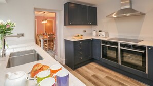 Eine moderne Küche mit dunklen Schränken, einer Edelstahlspüle und einem eingebauten Backofen.