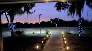 A pathway leading to a body of water, lined with trees and illuminated by small lights. - COUNTRYSIDE VACATION BY THE LAKE HOUSE CENTRAL FLORIDA (Frostproof)