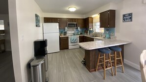A modern kitchen with a central island, stainless steel appliances, and wooden cabinets. - COUNTRYSIDE VACATION BY THE LAKE HOUSE CENTRAL FLORIDA (Frostproof)