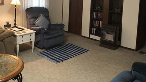 A living room with a sofa, a chair, a small table with a lamp, a bookshelf, and a carpet. - Horseshoe Cottage:  SKI, FISH, HIKE & BIKE: Paradise near all things outdoor! (Parsons)