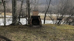 An outdoor brick fireplace surrounded by trees and a body of water. - Horseshoe Cottage:  SKI, FISH, HIKE & BIKE: Paradise near all things outdoor! (Parsons)