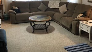 A living room with a sectional sofa, a glass coffee table, and a small white side table. - Horseshoe Cottage:  SKI, FISH, HIKE & BIKE: Paradise near all things outdoor! (Parsons)
