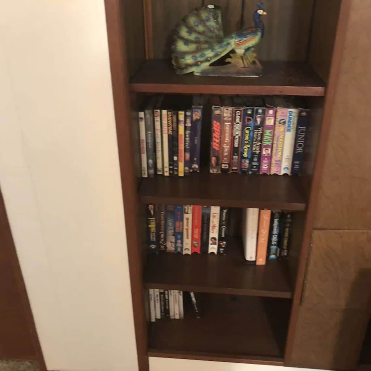 Een boekenplank met verschillende boeken en een decoratieve pauwbeeldje.