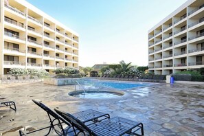 A hotel with a pool area, outdoor seating, and multiple balconies.