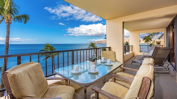 A balcony with a glass table set for two, two cushioned chairs, and a view of the ocean. - Sugar Beach Resort PH 14 Penthouse unit, Oceanfront complex, Ocean View, A/C (Kihei)
