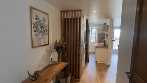 A hallway with a wooden bench, a vase with dried flowers, and a wooden partition.