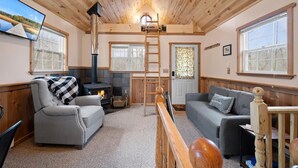 Un salon chaleureux avec une cheminée, un canapé, un fauteuil et un téléviseur fixé au mur.