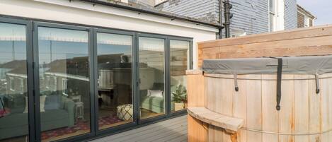 Eine Holzterrasse mit einer verglasten Veranda, einer Holzsauna und einer Bank.