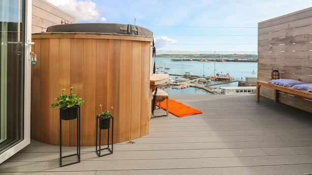 A wooden deck with a hot tub, potted plants, and a view of a marina. - 16 Arwenack Street (Falmouth)