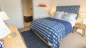 A bedroom with a bed, bedside tables, a wooden dresser, a bathroom door, and a patterned headboard. - 16 Arwenack Street (Falmouth)