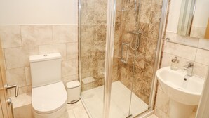 Une salle de bain avec une douche à parois de verre, des toilettes et un lavabo.