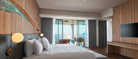 Quarto de hotel com uma cama grande, televisão de tela plana, varanda com vista e ventilador de teto.
