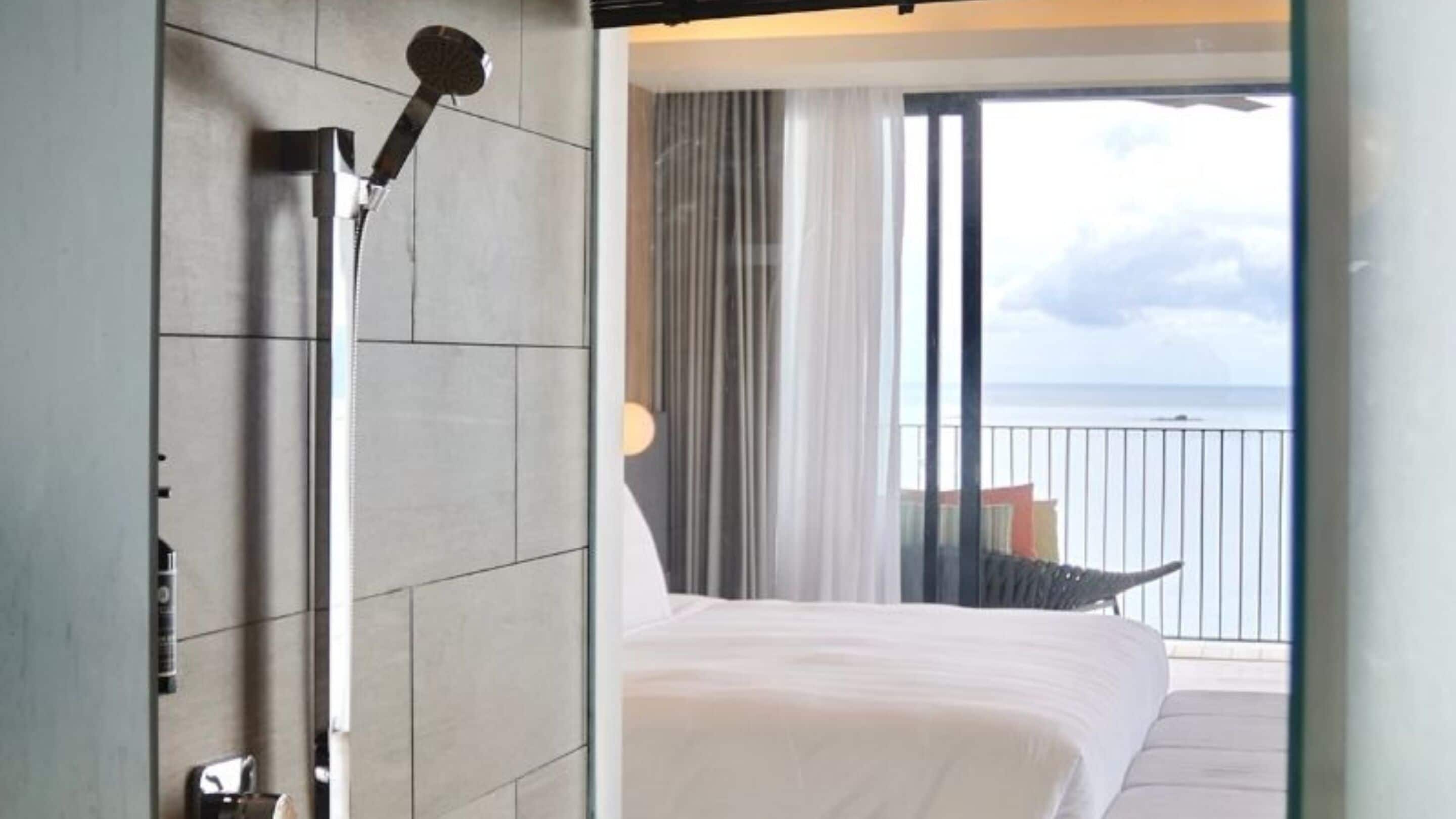 Ein Hotelzimmer mit Bett, Dusche und Meerblick.
