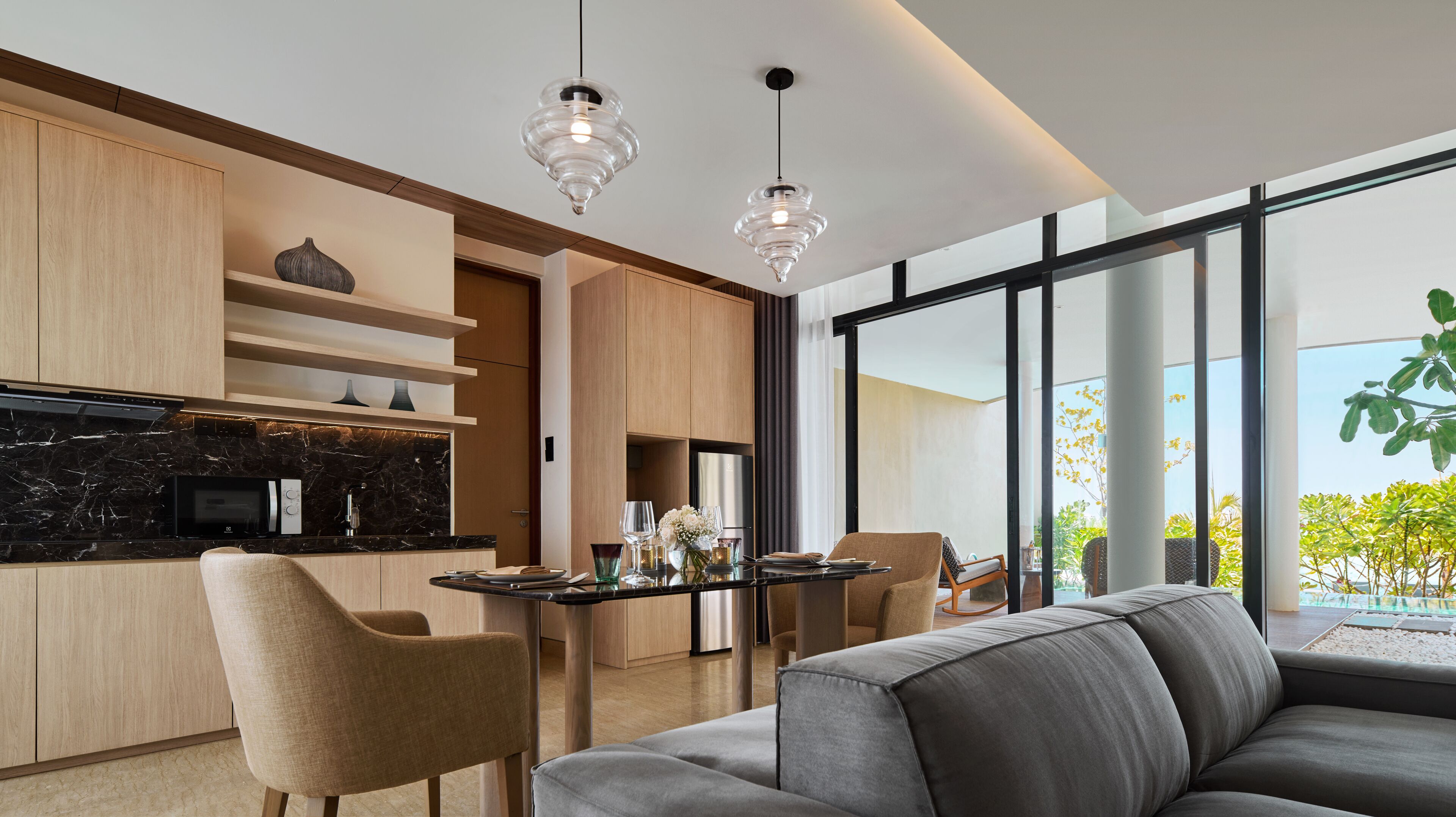 A modern kitchen with dark marble countertops, wooden cabinets, and a dining area with a table set for four.