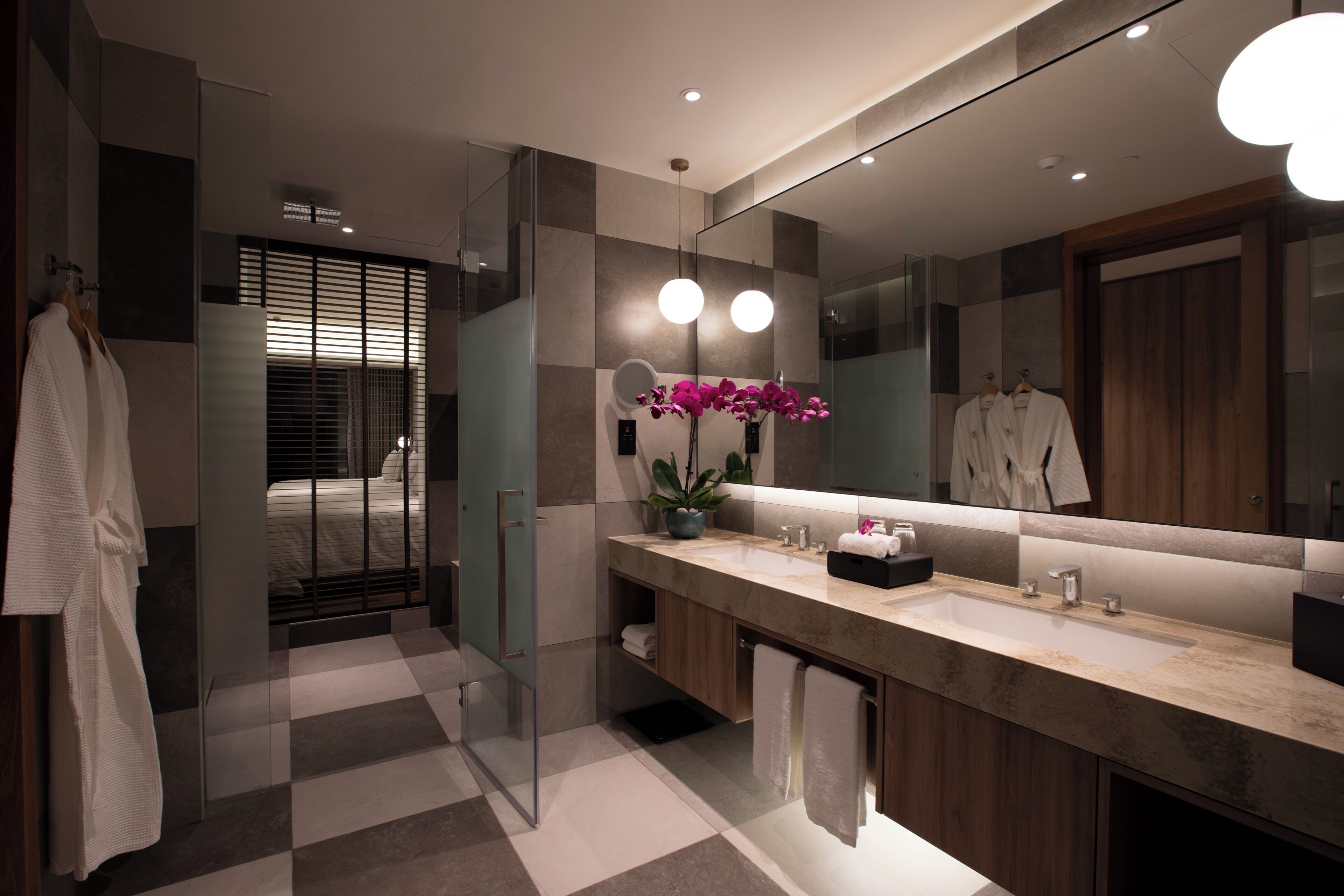 A modern bathroom with a large mirror, a vanity with a sink, and a shower area.