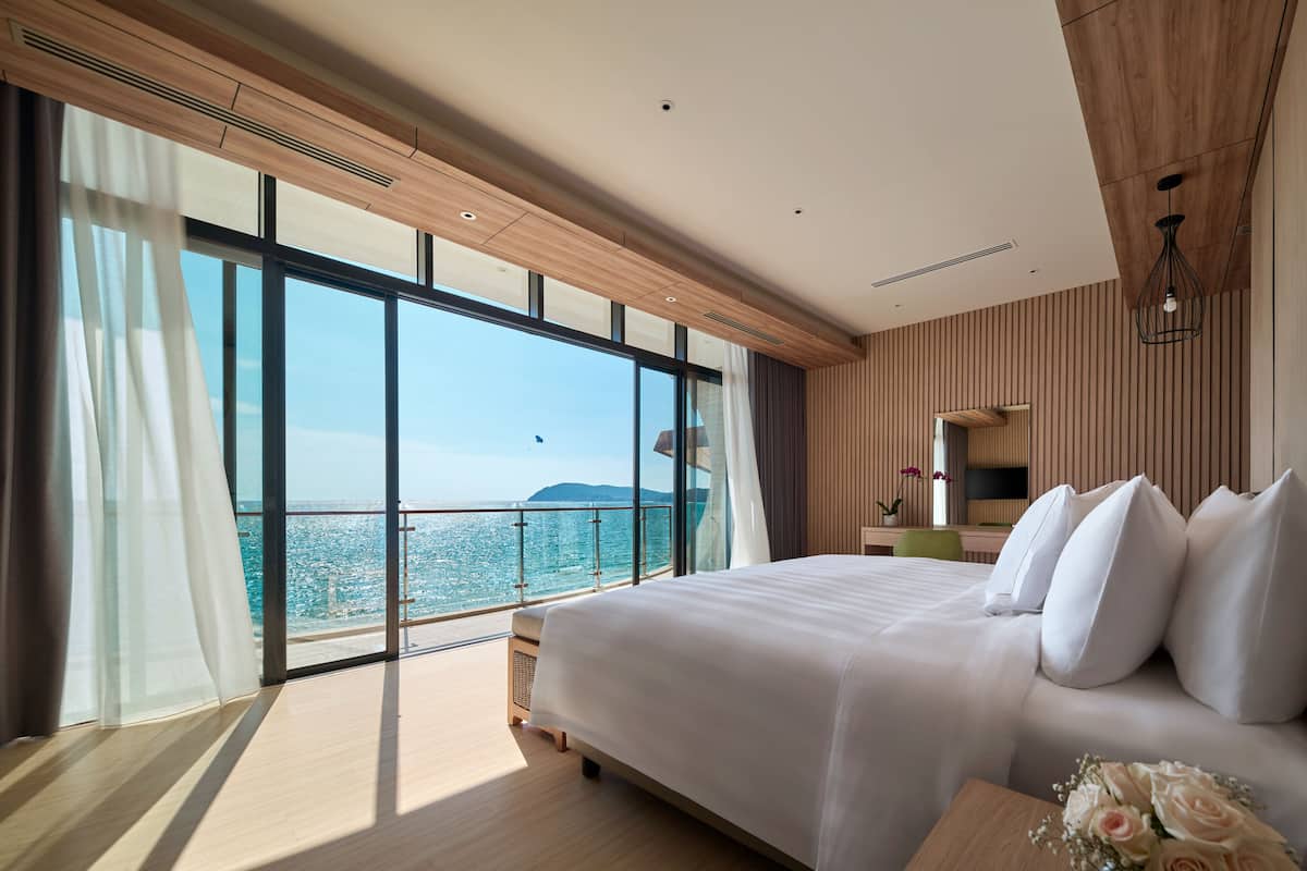 Une chambre d’hôtel moderne avec un grand lit, une vue sur la mer et un lambris en bois.