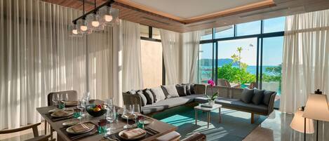Una sala de estar moderna con comedor, ventanas amplias y vista al mar.