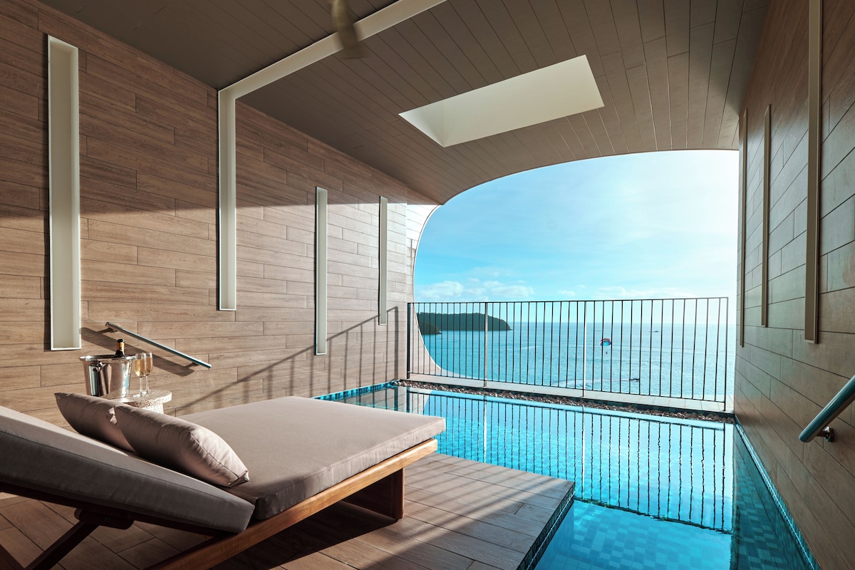A modern balcony with a pool, wooden flooring, and a clear view of the sea.