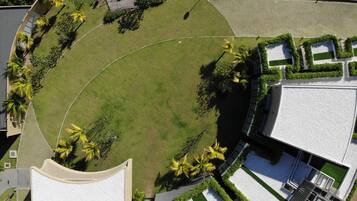 Vista aérea de un jardín ajardinado con césped circular, senderos y vegetación circundante.