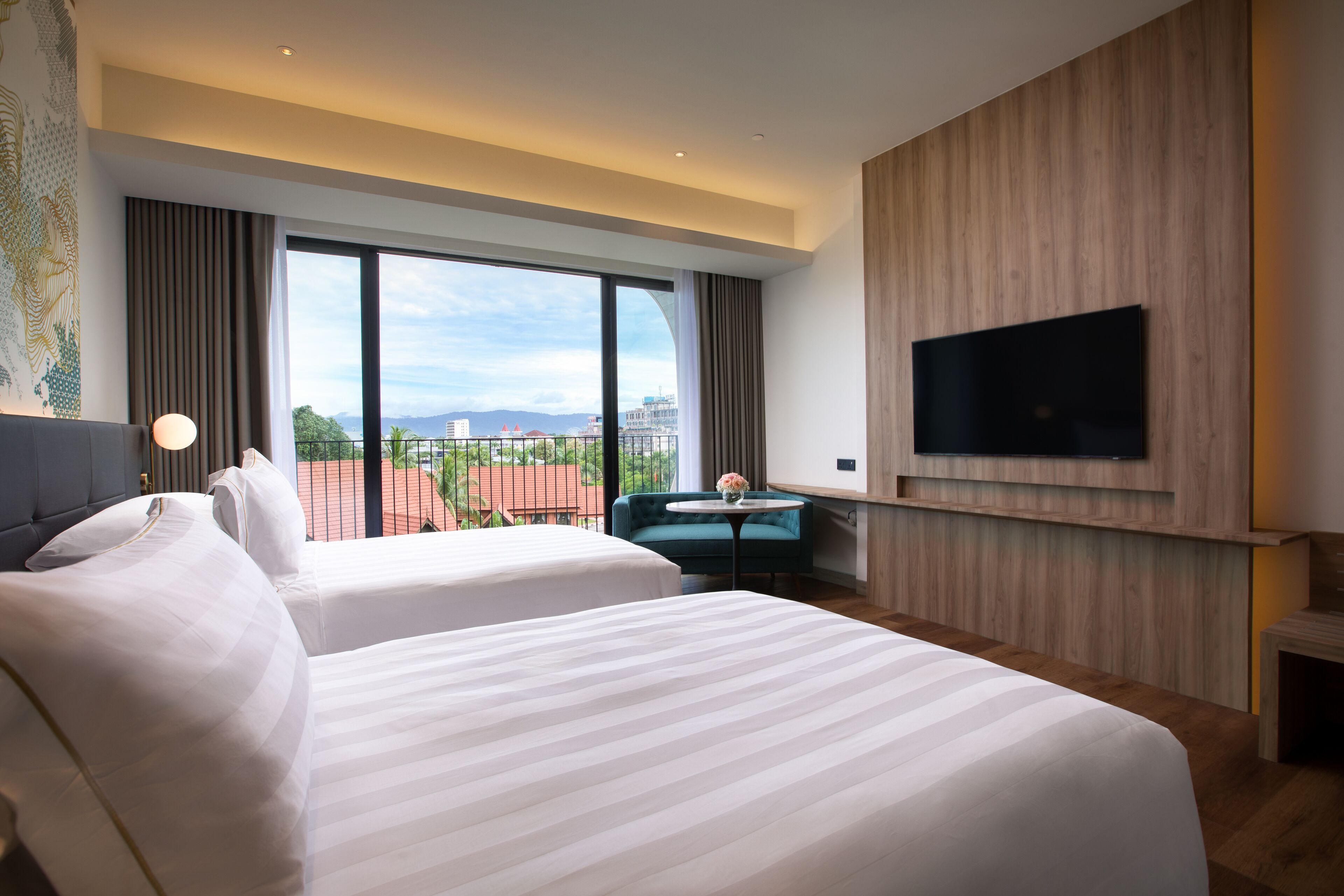 A hotel room with two beds, a TV mounted on the wall, and a view of the cityscape.