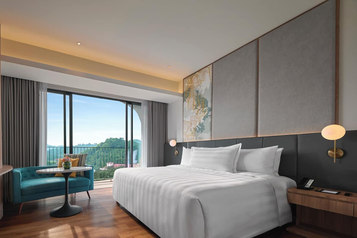 Une chambre d’hôtel moderne avec un grand lit, une petite table ronde, un canapé et un téléviseur.