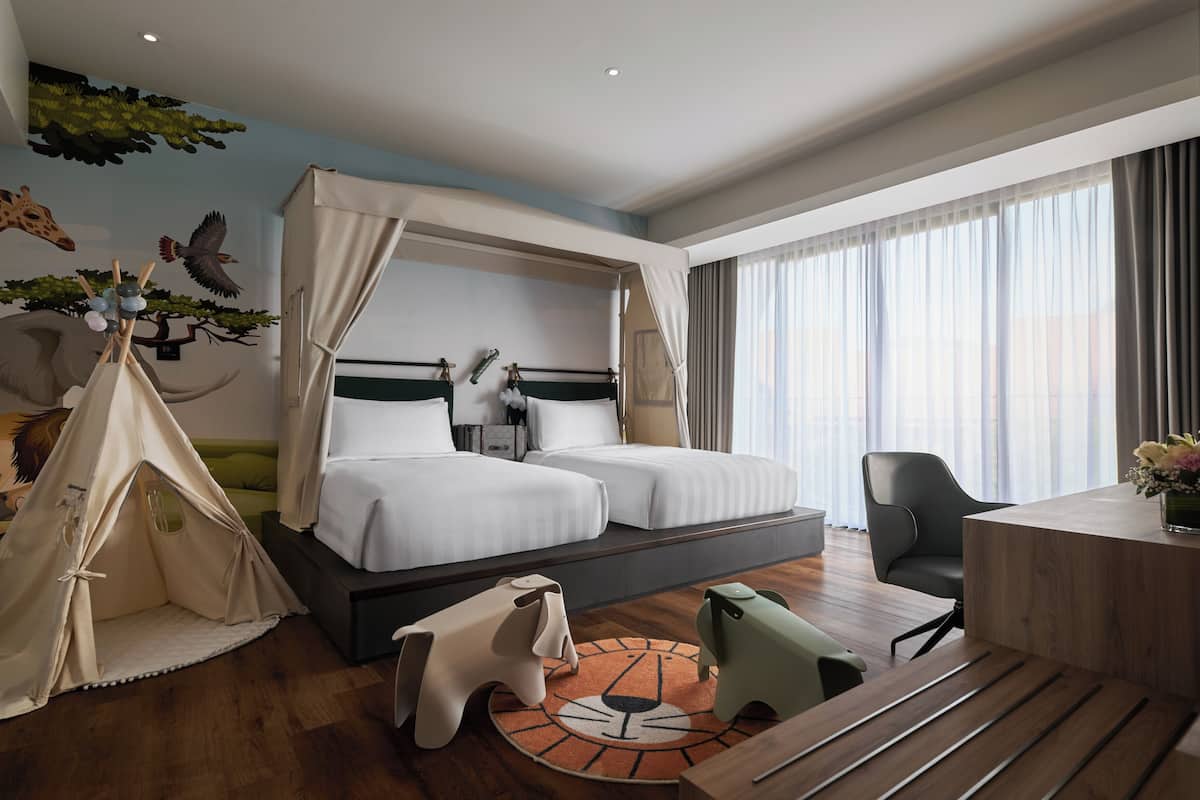 Une chambre d’hôtel avec un grand lit, un bureau, une chaise, une tente et un tapis.