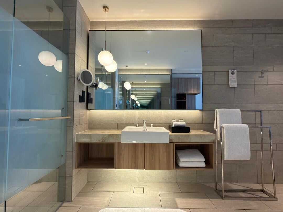 A modern bathroom with a large mirror, dual sinks, and a towel rack.