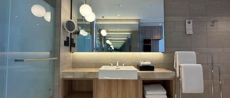 A modern bathroom with a large mirror, dual sinks, and a towel rack.