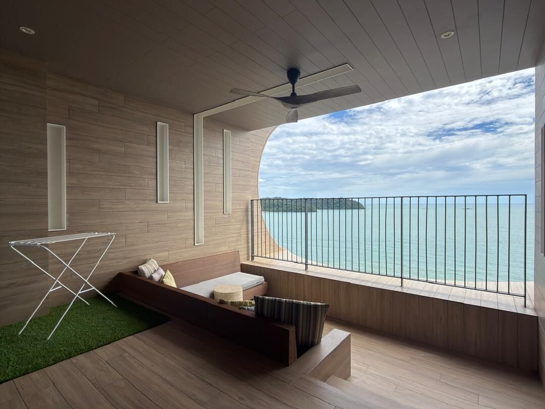 A modern room with a balcony overlooking a body of water, a ceiling fan, and a seating area with a small table.