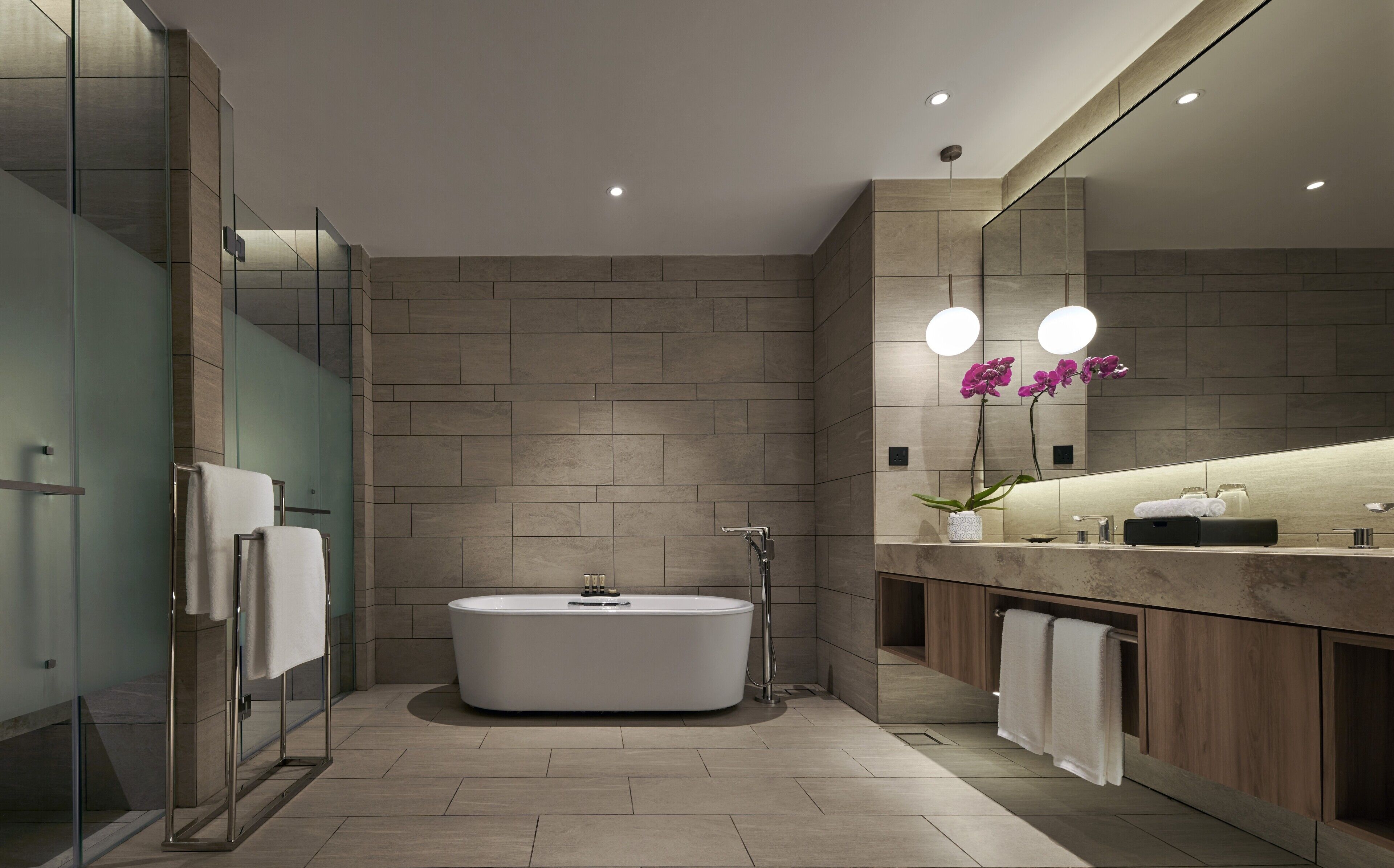 A modern bathroom with a freestanding bathtub, a glass shower enclosure, and a vanity with a mirror.