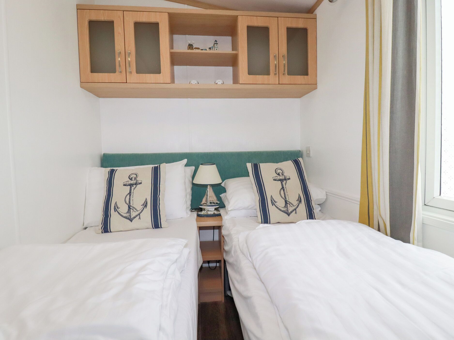 Habitación con cama doble, almohadas a juego, mesita de noche con lámpara y un mueble de madera sobre la cama.