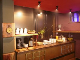 A breakfast bar with coffee makers, cups, and a clock.