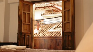 A room with a wooden door leading to a balcony with a tiled roof. - Hotel Montecristo Cusco (Cusco)